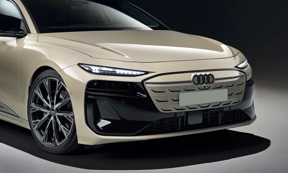 Фото Audi A6 Sportback e-tron (2024) — вид спереди, фото 9. Кузов в бежевом цвете: рисунок оптики и решётки задаёт узнаваемое «лицо» модели Audi A6 Sportback e-tron (2024) — вид спереди, фото 9
