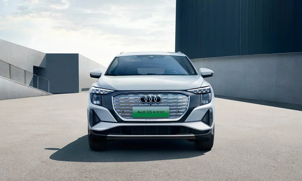 Фото Audi Q5 e-tron (2024) — вид спереди, фото 3. Передок в серебристом исполнении — крупная светотехника и выразительный бампер. Дневные ходовые огни включаются автоматически с запуском Audi Q5 e-tron (2024) — вид спереди, фото 3