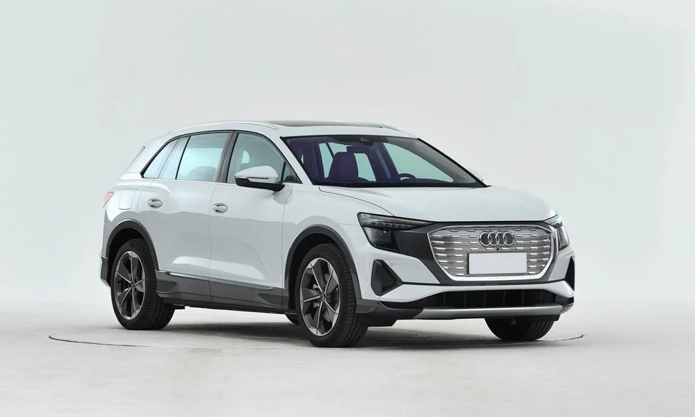 Фото Audi Q5 e-tron (2024) — вид спереди, фото 6. Кузов в белом цвете: рисунок оптики и решётки задаёт узнаваемое «лицо» модели. Рисунок ходовых огней — подпись модели, по нему её узнают в потоке Audi Q5 e-tron (2024) — вид спереди, фото 6