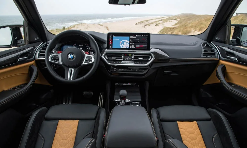 Фото BMW X3 M (2024) — передняя панель. Компоновка экранов, дефлекторов и консоли. Мягкие материалы верхнего яруса и вставки задают уровень интерьера BMW X3 M (2024) — передняя панель