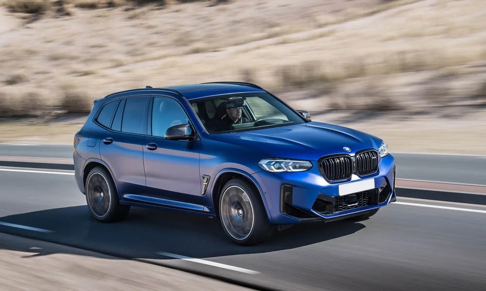Фото BMW X3 M (2024) — вид спереди, фото 4. Синий кузов, строгая симметрия оптики — базовый ракурс знакомства с дизайном. Дневные ходовые огни включаются автоматически с запуском BMW X3 M (2024) — вид спереди, фото 4