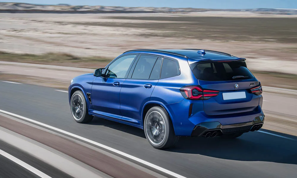 Фото BMW X3 M (2024) — вид сзади, фото 2. Синий кузов сзади — фонари и бампер определяют ночной образ модели. Насадки выхлопа или их имитация внизу бампера различают версии BMW X3 M (2024) — вид сзади, фото 2