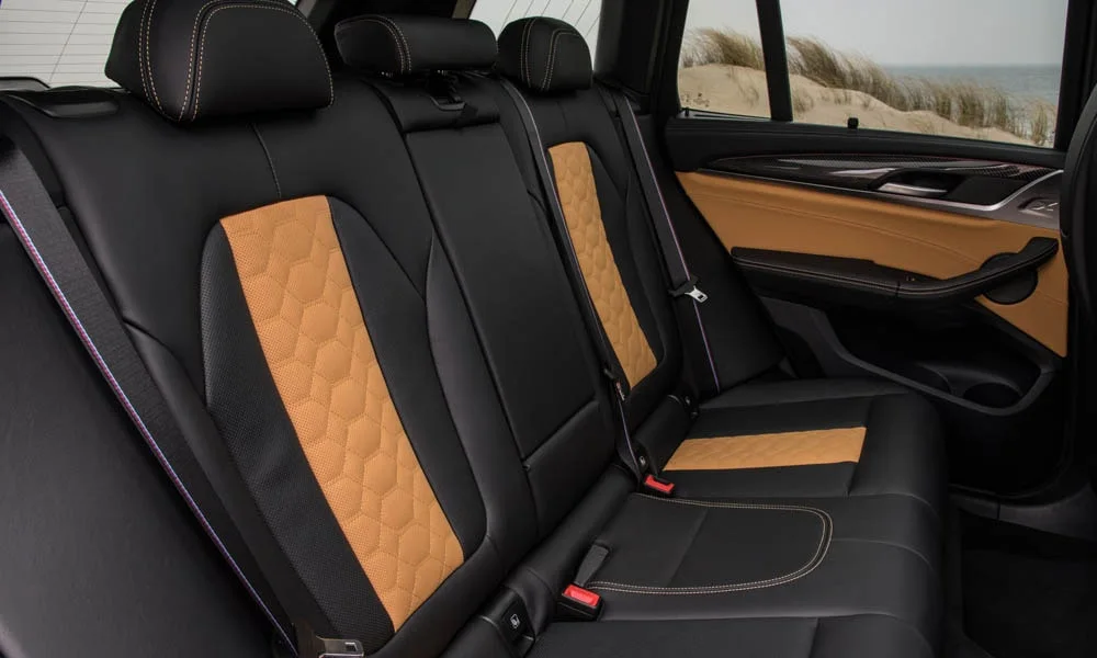 Фото BMW X3 M (2024) — задние сиденья. Посадка второго ряда: подголовники и подлокотник BMW X3 M (2024) — задние сиденья