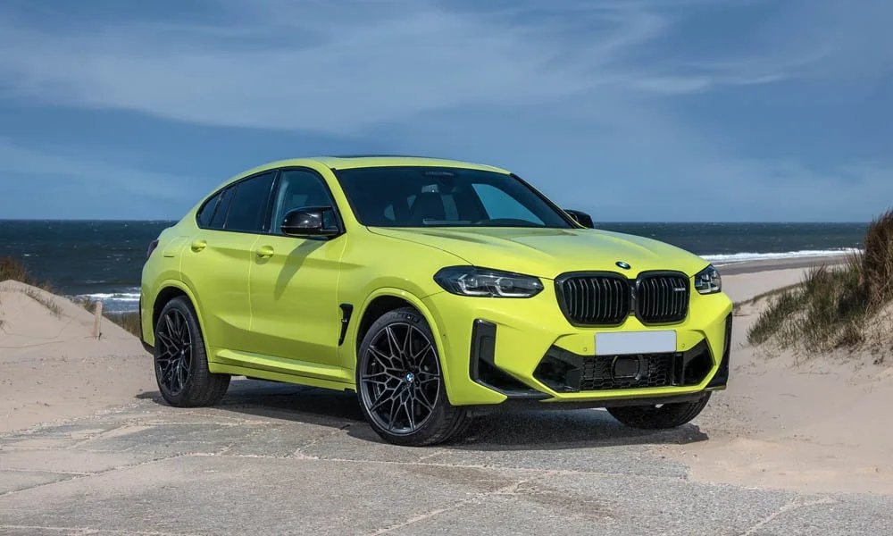 Фото BMW X4 M (2024) — вид спереди, фото 3. Кузов в жёлтом цвете: рисунок оптики и решётки задаёт узнаваемое «лицо» модели. Дневные ходовые огни включаются автоматически с запуском BMW X4 M (2024) — вид спереди, фото 3
