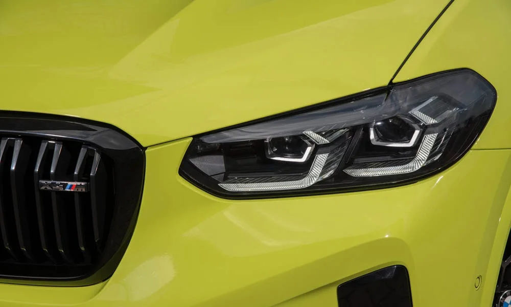 Фото BMW X4 M (2024) — вид спереди, фото 5. Передок в жёлтом исполнении — крупная светотехника и выразительный бампер. Дневные ходовые огни включаются автоматически с запуском BMW X4 M (2024) — вид спереди, фото 5