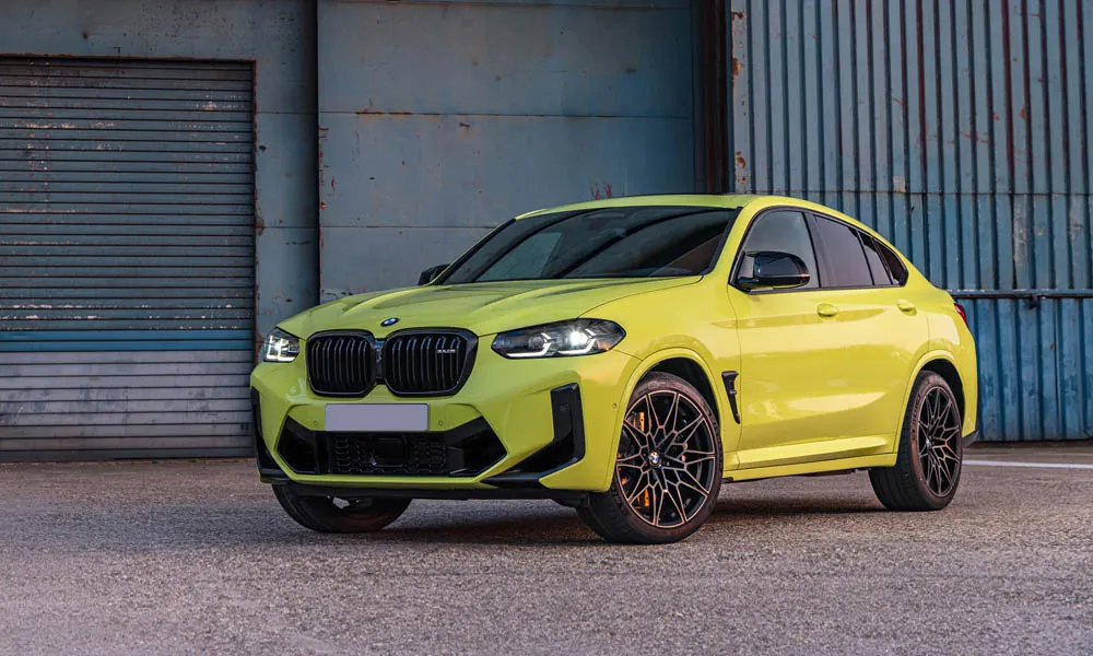 Фото BMW X4 M (2024) — вид спереди, фото 7. Передок в жёлтом исполнении — крупная светотехника и выразительный бампер. Рисунок ходовых огней — подпись модели, по нему её узнают в потоке BMW X4 M (2024) — вид спереди, фото 7
