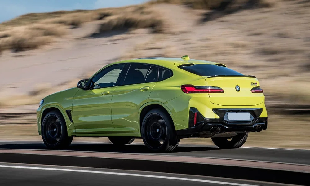 Фото BMW X4 M (2024) — вид сзади, фото 3. Линия крыши, стойки и задняя дверь в жёлтом исполнении. Насадки выхлопа или их имитация внизу бампера различают версии BMW X4 M (2024) — вид сзади, фото 3