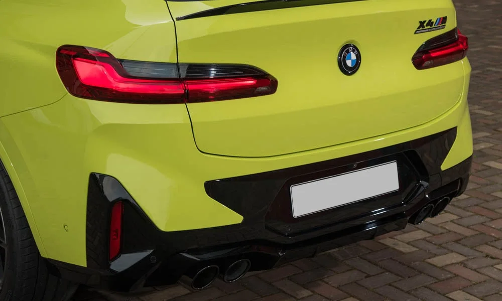 Фото BMW X4 M (2024) — вид сзади, фото 7. Жёлтый кузов сзади — фонари и бампер определяют ночной образ модели. Насадки выхлопа или их имитация внизу бампера различают версии BMW X4 M (2024) — вид сзади, фото 7