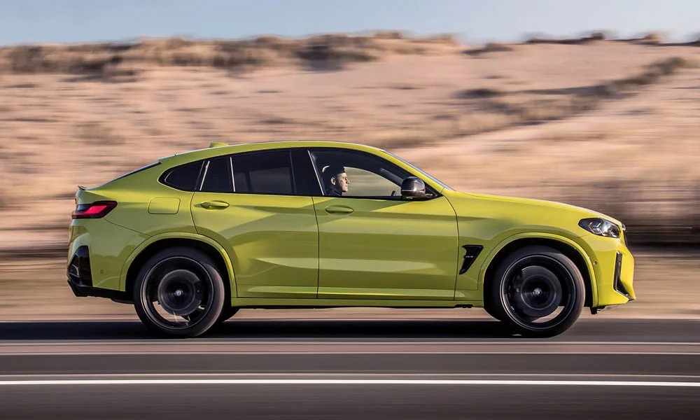 Фото BMW X4 M (2024) — вид сбоку, фото 3. Сбоку читаются линия остекления и характер выштамповок на жёлтом кузове BMW X4 M (2024) — вид сбоку, фото 3