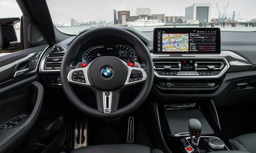 Фото BMW X4 M (2024) — руль. Обшивка обода и компоновка спиц крупным планом. Клавиши на спицах управляют медиа, круизом и ассистентами — руки остаются на руле BMW X4 M (2024) — руль
