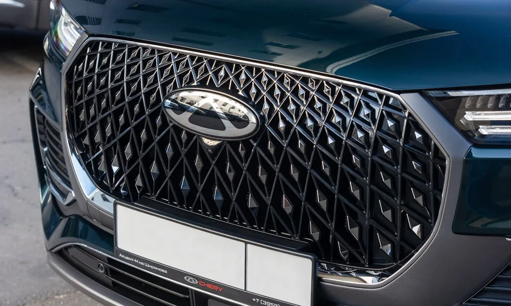 Фото Chery Tiggo 8 Pro Plug-in Hybrid (2023) — решётка радиатора. Фирменный рисунок облицовки — визитная карточка марки Chery Tiggo 8 Pro Plug-in Hybrid (2023) — решётка радиатора