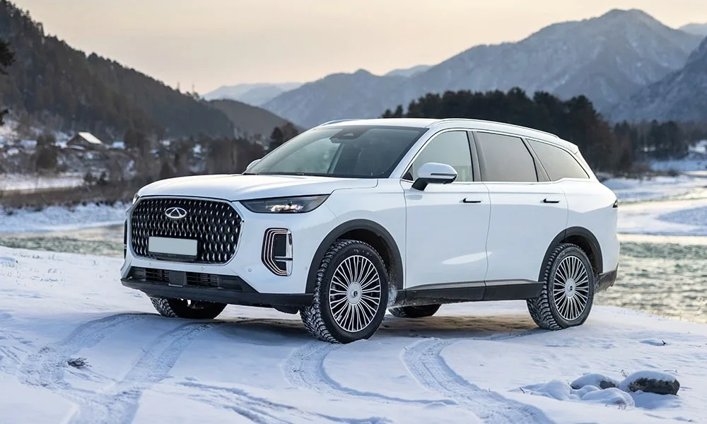 Фото Chery Tiggo 9 (2024) — вид спереди, фото 4. Белый кузов, строгая симметрия оптики — базовый ракурс знакомства с дизайном. Дневные ходовые огни включаются автоматически с запуском Chery Tiggo 9 (2024) — вид спереди, фото 4