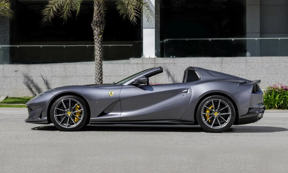 Фото Ferrari 812 GTS — вид сбоку, фото 3. Серый кузов в профиль — пропорции, высота посадки и дизайн дисков. Хромированные или чёрные молдинги окон отличают комплектации Ferrari 812 GTS — вид сбоку, фото 3
