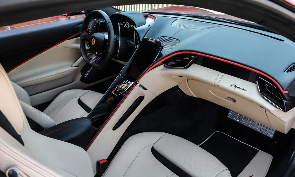 Фото Ferrari Roma — передняя панель. Панель в красно-чёрной отделке — видна компоновка экранов и органов управления. Мягкие материалы верхнего яруса и вставки задают уровень интерьера Ferrari Roma — передняя панель