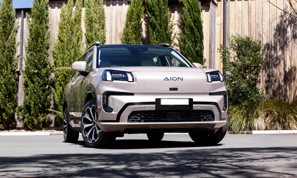Фото GAC Aion V (2026) — вид спереди, фото 6. Бежевый кузов, строгая симметрия оптики — базовый ракурс знакомства с дизайном. Дневные ходовые огни включаются автоматически с запуском GAC Aion V (2026) — вид спереди, фото 6