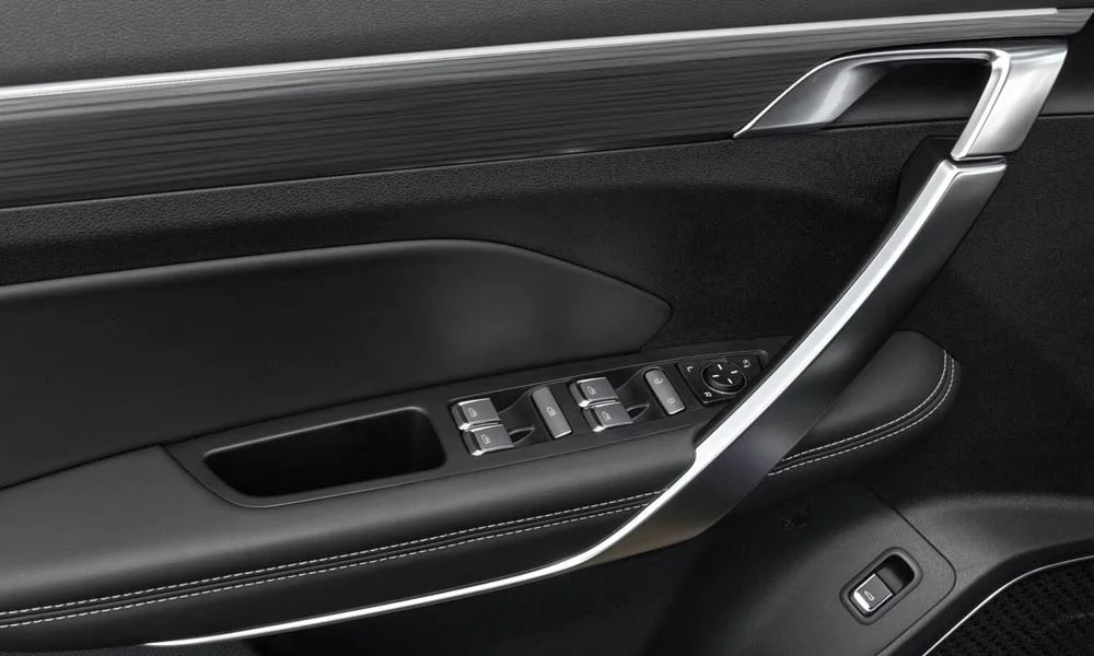 Фото Geely Atlas Pro — дверная карта. Дверная карта в тёмной отделке: подлокотник, динамик и блок стеклоподъёмников. Решётка динамика в двери — часть штатной акустики Geely Atlas Pro — дверная карта