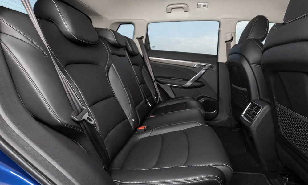 Фото Geely Atlas Pro — задние сиденья. Задний диван в перфорированной коже: посадка и центральный подлокотник. Спинки складываются под длинные грузы у большинства версий Geely Atlas Pro — задние сиденья