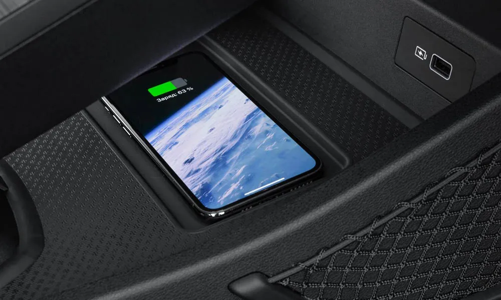 Фото Geely Atlas Pro — беспроводная зарядка. Ниша с беспроводной зарядкой в центральной консоли. Прорезиненное покрытие удерживает телефон в поворотах; мощность зарядки — в характеристиках версии Geely Atlas Pro — беспроводная зарядка
