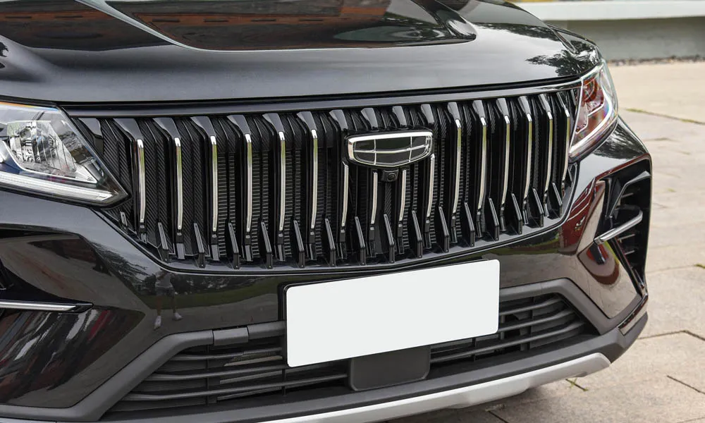 Фото Geely Emgrand X7 (2024) — решётка радиатора. Рисунок решётки: сетка, ламели или глухая панель у электроверсий. За решёткой у многих комплектаций стоит радар адаптивного круиз-контроля Geely Emgrand X7 (2024) — решётка радиатора