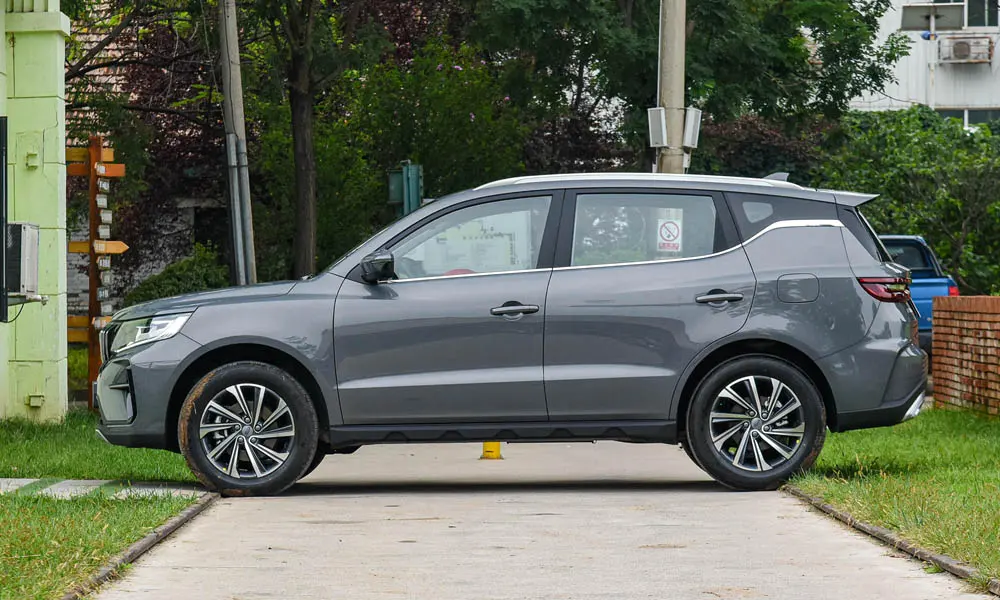 Фото Geely Emgrand X7 (2024) — вид сбоку, фото 2. Серый кузов в профиль — пропорции, высота посадки и дизайн дисков. Хромированные или чёрные молдинги окон отличают комплектации Geely Emgrand X7 (2024) — вид сбоку, фото 2