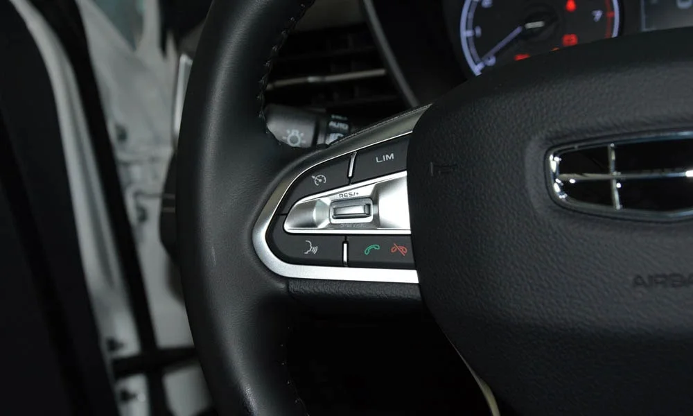 Фото Geely Emgrand X7 (2024) — руль, фото 2. Обшивка обода и компоновка спиц крупным планом. Клавиши на спицах управляют медиа, круизом и ассистентами — руки остаются на руле Geely Emgrand X7 (2024) — руль, фото 2