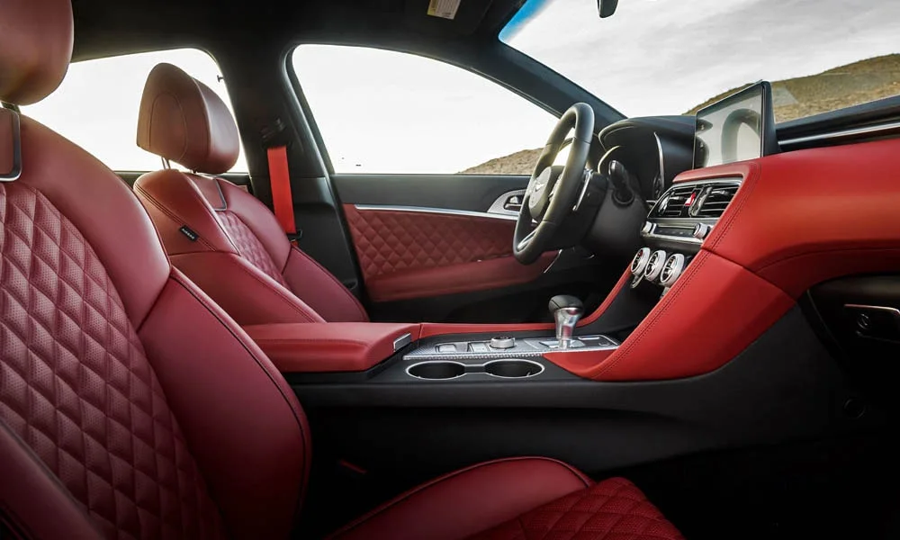 Фото Genesis G70 Shooting Brake (2022) — интерьер. Салон в красно-чёрной отделке: архитектура передней панели, консоль и кресла. Уровень отделки читается по стыкам панелей и мягким поверхностям в зонах касания Genesis G70 Shooting Brake (2022) — интерьер