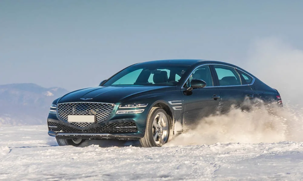 Фото Genesis G80 — вид спереди, фото 5. Чёрный кузов, строгая симметрия оптики — базовый ракурс знакомства с дизайном. Рисунок ходовых огней — подпись модели, по нему её узнают в потоке Genesis G80 — вид спереди, фото 5