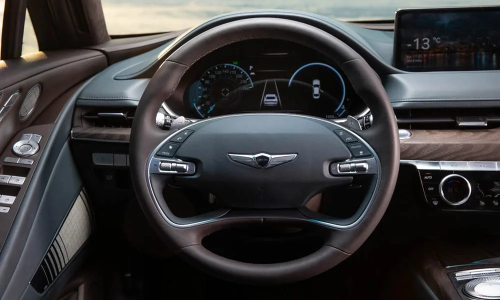 Фото Genesis G80 — руль. Обшивка обода и компоновка спиц крупным планом. Клавиши на спицах управляют медиа, круизом и ассистентами — руки остаются на руле Genesis G80 — руль