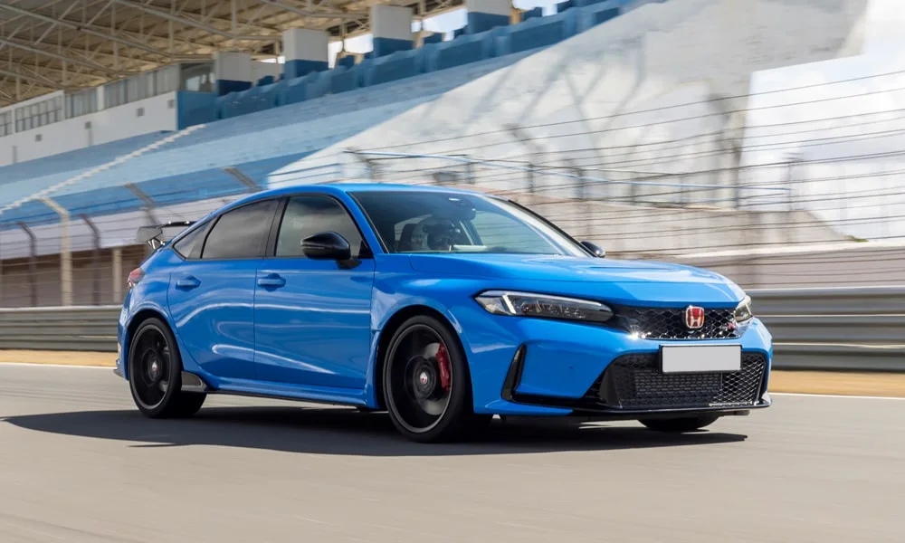 Фото Honda Civic Type R (2024) — вид спереди, фото 5. Кузов в синем цвете: рисунок оптики и решётки задаёт узнаваемое «лицо» модели. Дневные ходовые огни включаются автоматически с запуском Honda Civic Type R (2024) — вид спереди, фото 5