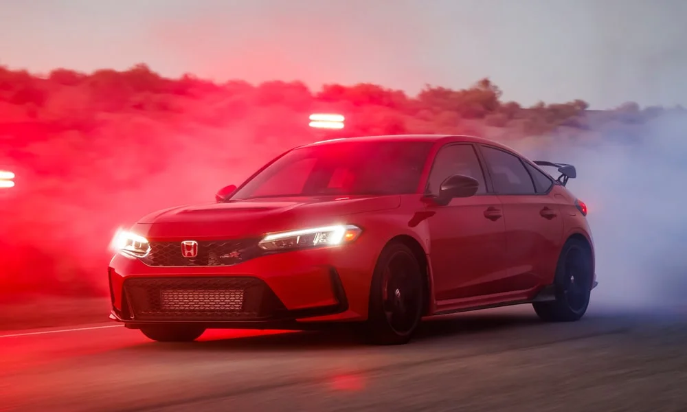 Фото Honda Civic Type R (2024) — вид спереди, фото 9. Кузов в красном цвете: рисунок оптики и решётки задаёт узнаваемое «лицо» модели Honda Civic Type R (2024) — вид спереди, фото 9