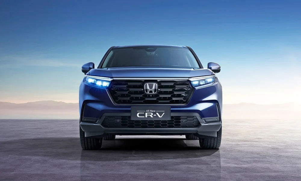 Фото Honda CR-V (2024) — вид спереди, фото 7. Кузов в синем цвете: рисунок оптики и решётки задаёт узнаваемое «лицо» модели. Рисунок ходовых огней — подпись модели, по нему её узнают в потоке Honda CR-V (2024) — вид спереди, фото 7