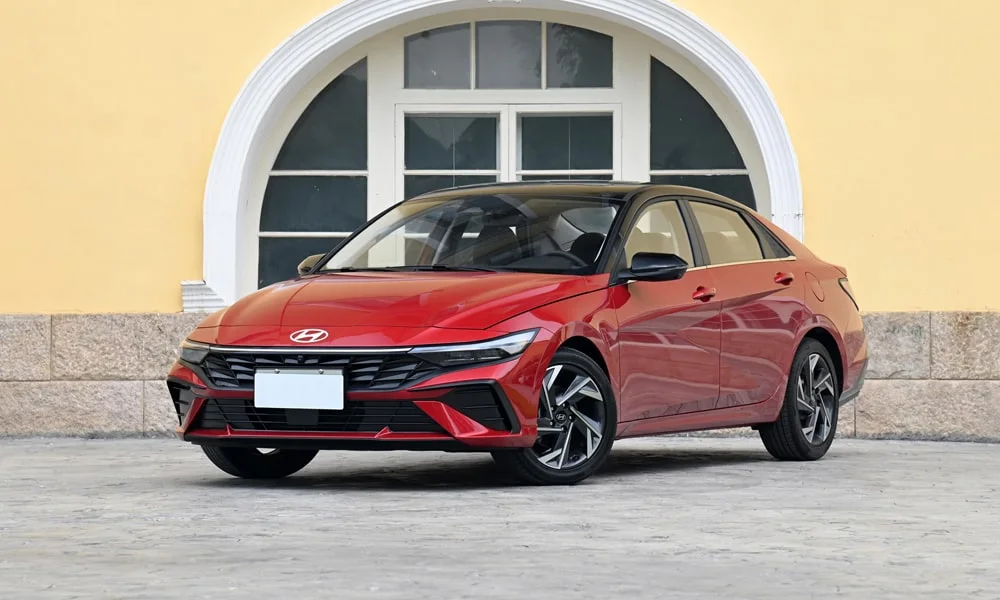 Фото Hyundai Elantra (2024) — вид спереди, фото 5. Красный кузов, строгая симметрия оптики — базовый ракурс знакомства с дизайном Hyundai Elantra (2024) — вид спереди, фото 5