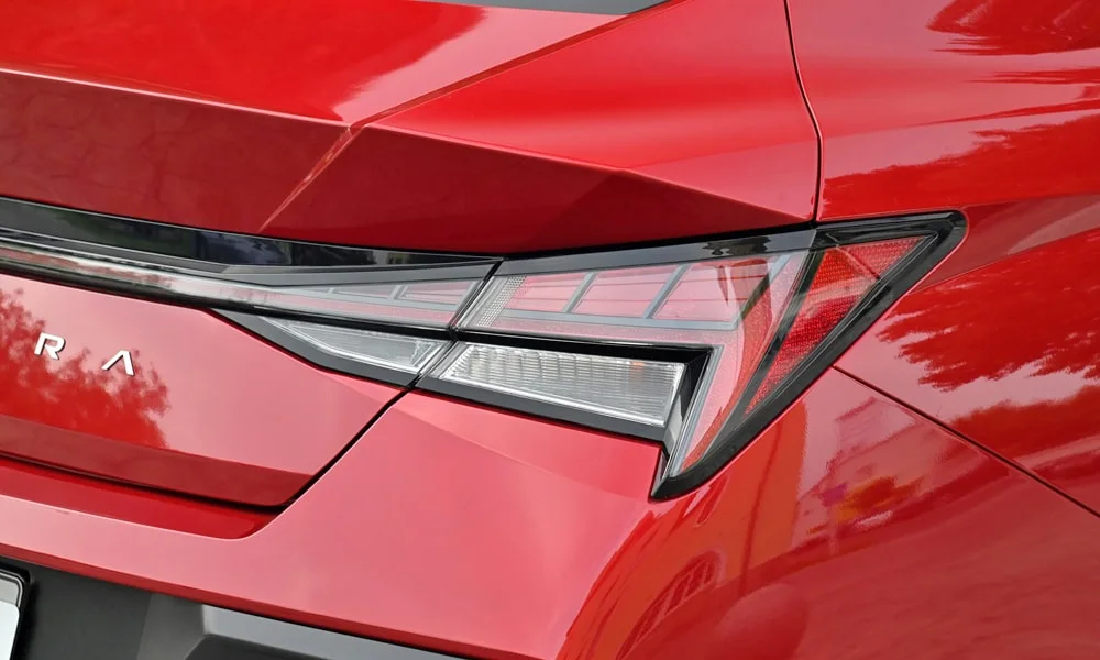 Фото Hyundai Elantra (2024) — задние фонари. Рассеиватель фонаря вблизи: компоновка секций габарита, стопа и поворотника. Динамические поворотники с бегущей индикацией встречаются в старших комплектациях Hyundai Elantra (2024) — задние фонари