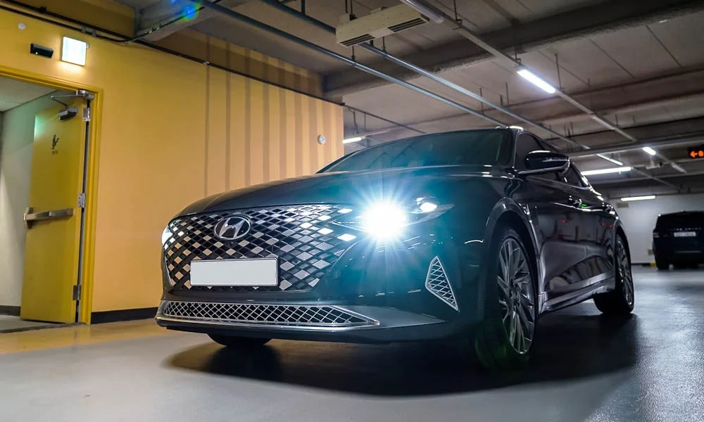 Фото Hyundai Grandeur — вид спереди, фото 2. Кузов в чёрном цвете: рисунок оптики и решётки задаёт узнаваемое «лицо» модели. Рисунок ходовых огней — подпись модели, по нему её узнают в потоке Hyundai Grandeur — вид спереди, фото 2