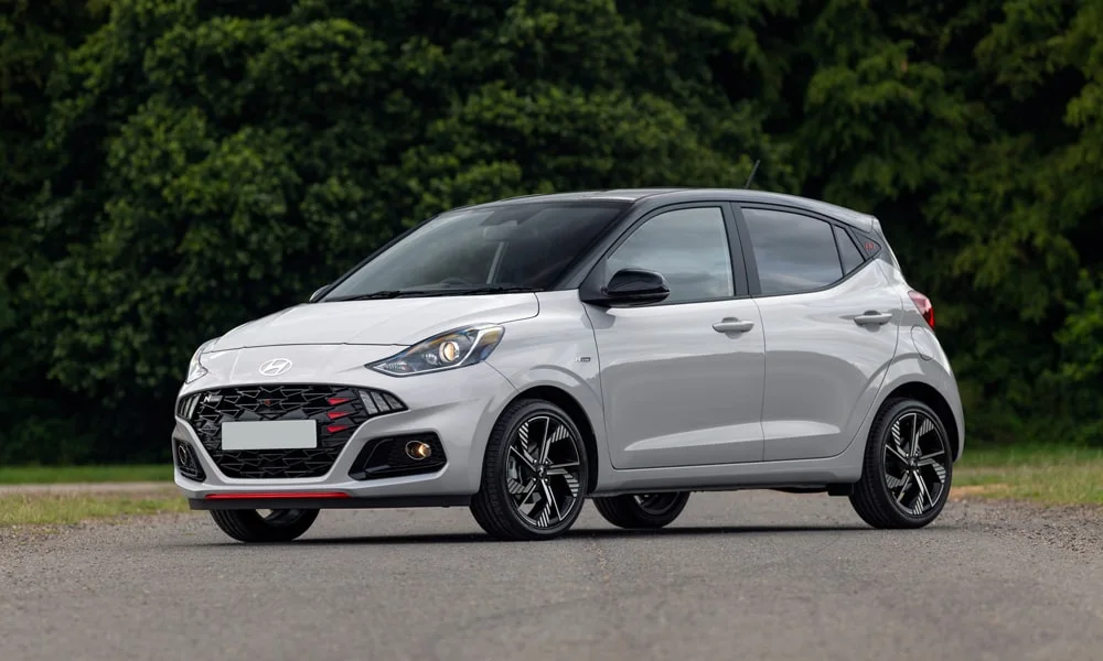 Фото Hyundai i10 — вид спереди, фото 6. Кузов в белом цвете: рисунок оптики и решётки задаёт узнаваемое «лицо» модели. Рисунок ходовых огней — подпись модели, по нему её узнают в потоке Hyundai i10 — вид спереди, фото 6