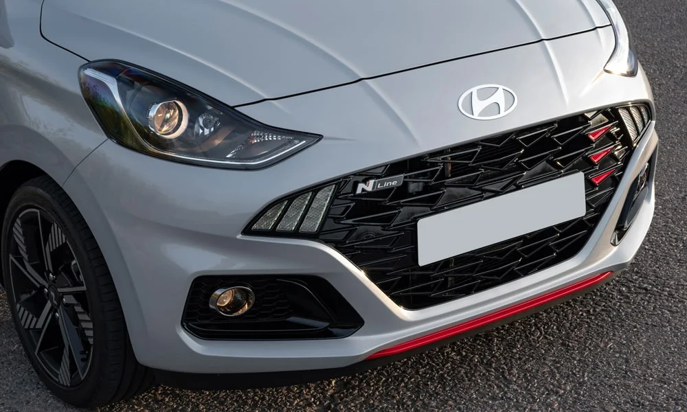Фото Hyundai i10 — решётка радиатора, фото 2. Фирменный рисунок облицовки — визитная карточка марки. Активные жалюзи за решёткой закрываются на трассе ради аэродинамики — есть у ряда моделей Hyundai i10 — решётка радиатора, фото 2