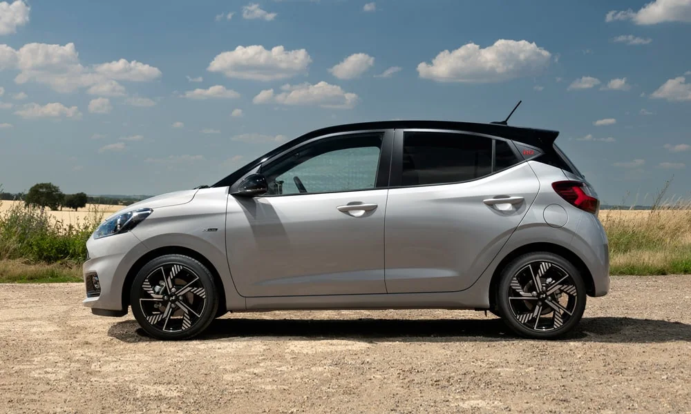 Фото Hyundai i10 — вид сбоку, фото 3. Серебристый кузов в профиль — пропорции, высота посадки и дизайн дисков. Длинная база — простор второго ряда; короткие свесы упрощают парковку Hyundai i10 — вид сбоку, фото 3