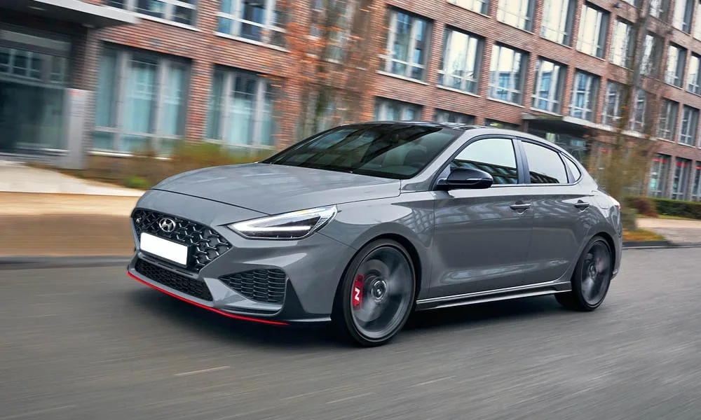 Фото Hyundai i30 Fastback N (2024) — вид спереди, фото 8. Кузов в сером цвете: рисунок оптики и решётки задаёт узнаваемое «лицо» модели Hyundai i30 Fastback N (2024) — вид спереди, фото 8