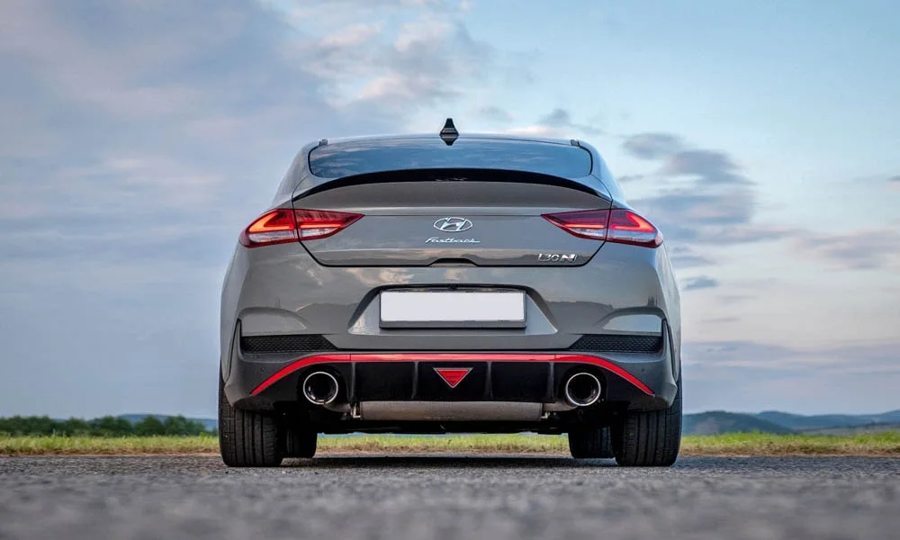 Фото Hyundai i30 Fastback N (2024) — вид сзади, фото 5. Линия крыши, стойки и задняя дверь в сером исполнении. Насадки выхлопа или их имитация внизу бампера различают версии Hyundai i30 Fastback N (2024) — вид сзади, фото 5