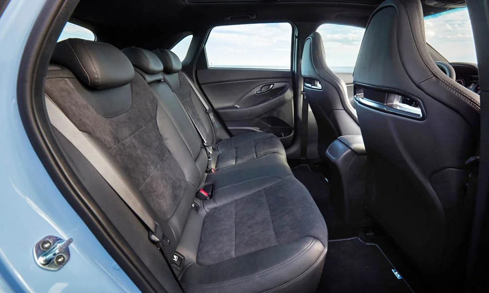 Фото Hyundai i30 Fastback N (2024) — задние сиденья. Посадка второго ряда: подголовники и подлокотник. Плоский пол упрощает посадку втроём Hyundai i30 Fastback N (2024) — задние сиденья