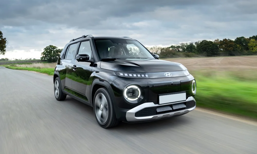 Фото Hyundai Inster — вид спереди, фото 4. Кузов в чёрном цвете: рисунок оптики и решётки задаёт узнаваемое «лицо» модели. Рисунок ходовых огней — подпись модели, по нему её узнают в потоке Hyundai Inster — вид спереди, фото 4