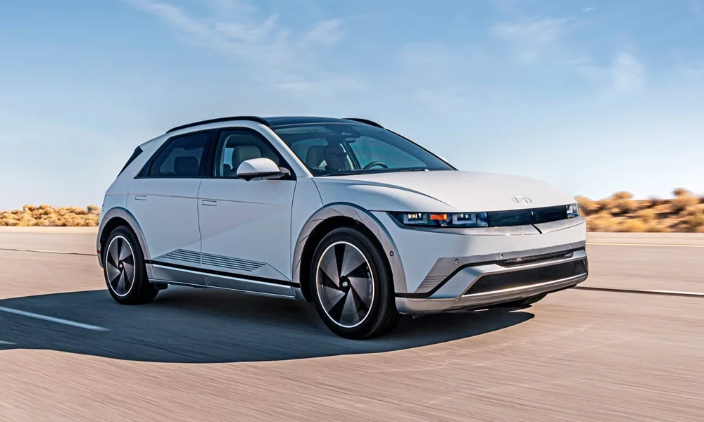 Фото Hyundai IONIQ 5 (2024) — вид спереди, фото 6. Кузов в белом цвете: рисунок оптики и решётки задаёт узнаваемое «лицо» модели. Дневные ходовые огни включаются автоматически с запуском Hyundai IONIQ 5 (2024) — вид спереди, фото 6