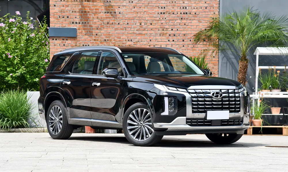 Фото Hyundai Palisade (2024) — вид спереди, фото 3. Кузов в чёрном цвете: рисунок оптики и решётки задаёт узнаваемое «лицо» модели. Рисунок ходовых огней — подпись модели, по нему её узнают в потоке Hyundai Palisade (2024) — вид спереди, фото 3