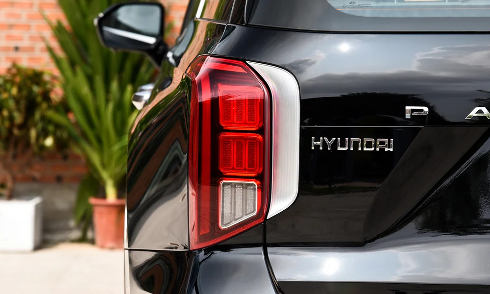Фото Hyundai Palisade (2024) — вид сзади, фото 4. Линия крыши, стойки и задняя дверь в чёрном исполнении. Насадки выхлопа или их имитация внизу бампера различают версии Hyundai Palisade (2024) — вид сзади, фото 4