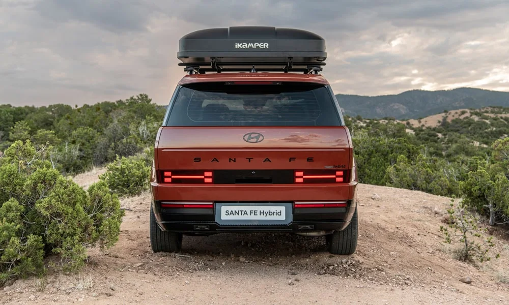 Фото Hyundai Santa Fe (2024) — вид сзади, фото 4. Линия крыши, стойки и задняя дверь в красном исполнении. Насадки выхлопа или их имитация внизу бампера различают версии Hyundai Santa Fe (2024) — вид сзади, фото 4