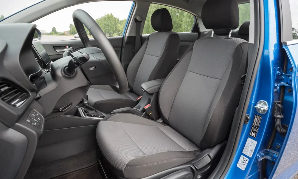 Фото Hyundai Solaris — передние сиденья. Водительское и пассажирское кресла: обивка из практичной ткани, профиль с боковой поддержкой. Перфорация обивки нужна для вентиляции — функции старших комплектаций Hyundai Solaris — передние сиденья