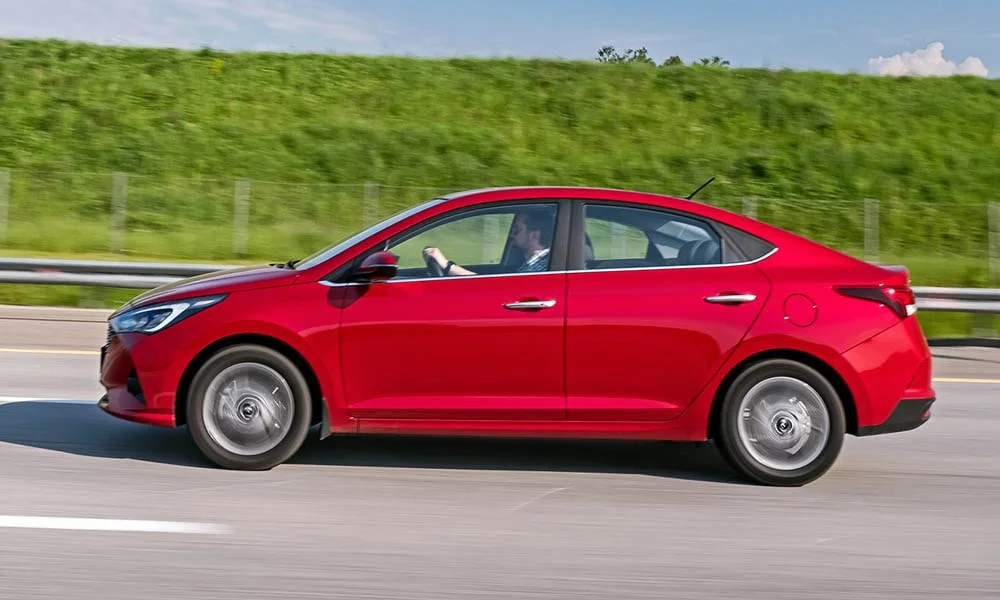 Фото Hyundai Solaris — вид сбоку, фото 3. Сбоку читаются линия остекления и характер выштамповок на красном кузове Hyundai Solaris — вид сбоку, фото 3