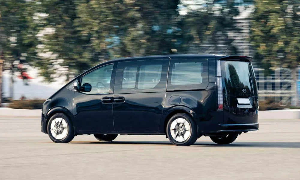Фото Hyundai Staria (2022) — вид сзади, фото 4. Чёрный кузов сзади — фонари и бампер определяют ночной образ модели. Насадки выхлопа или их имитация внизу бампера различают версии Hyundai Staria (2022) — вид сзади, фото 4