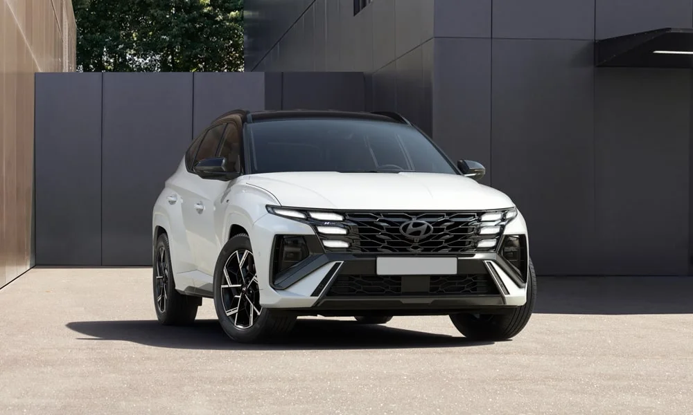 Фото Hyundai Tucson N Line (2024) — вид спереди, фото 10. Передок в белом исполнении — крупная светотехника и выразительный бампер. Рисунок ходовых огней — подпись модели, по нему её узнают в потоке Hyundai Tucson N Line (2024) — вид спереди, фото 10