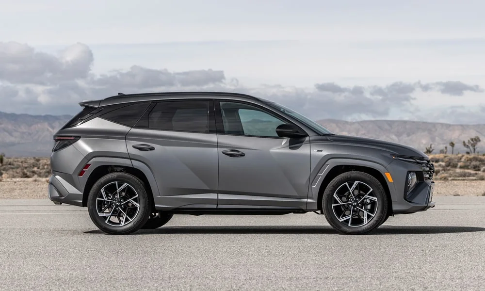 Фото Hyundai Tucson N Line (2024) — вид сбоку. Сбоку читаются линия остекления и характер выштамповок на сером кузове Hyundai Tucson N Line (2024) — вид сбоку